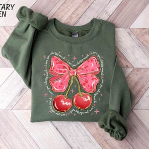 a green shirt with a pink bow and cherries on it