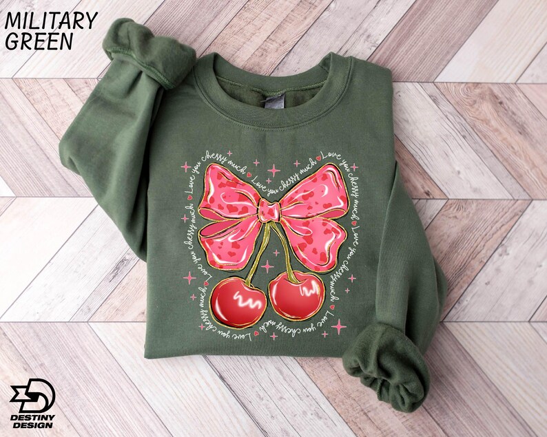 a green shirt with a pink bow and cherries on it