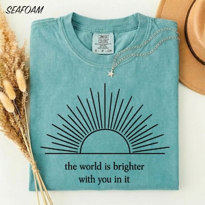 El mundo es más brillante contigo en él. Camiseta con estampado inspirador sobre salud mental y colores que brindan comodidad. Regalo ideal para amigos y consejeros.