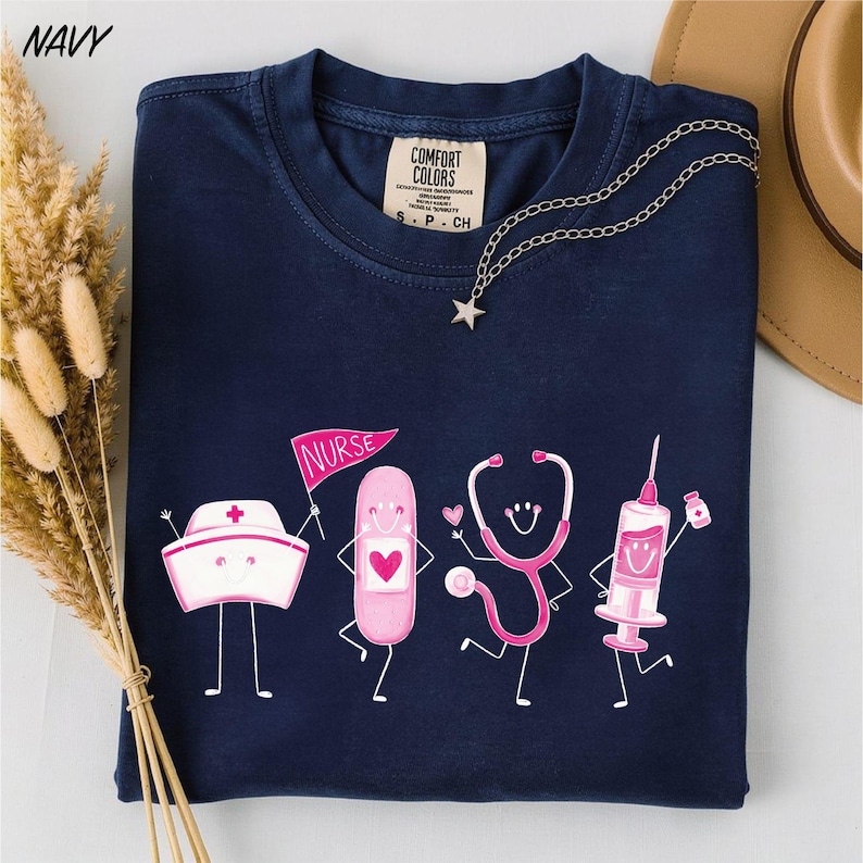 A navy blue t-shirt with a graphic design depicting four cartoon-style medical professionals, including a nurse, a stethoscope, a syringe, and a heart.