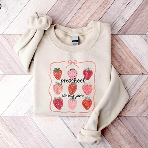 a sweater with strawberries on it on a wooden floor
