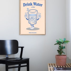 K&ouml;nnte beinhalten: Ein hellpfirsichfarbener Poster mit einem blauen Cartoon-Glas Wasser mit einem l&auml;chelnden Gesicht und Peace-Zeichen. Der Text auf dem Poster lautet "Drink Water More Daily Reminder".