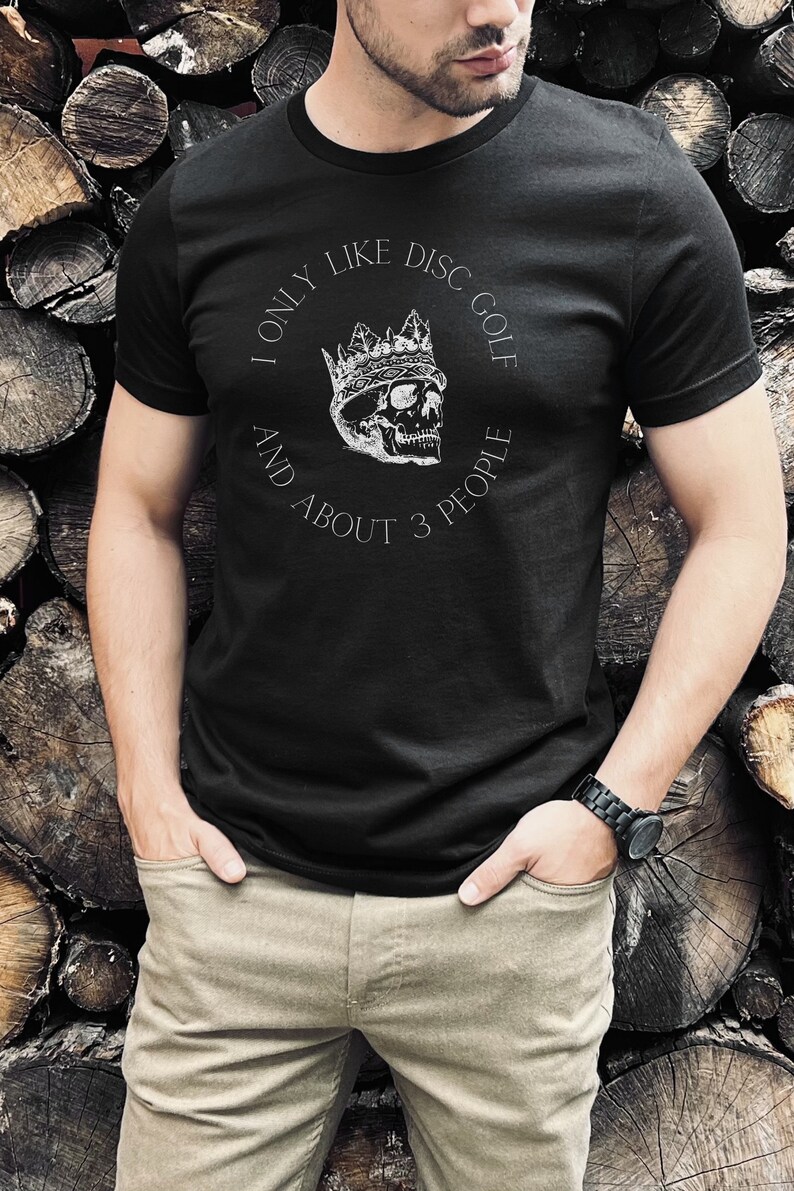 Peut inclure: Un t-shirt noir avec un graphique blanc d'un cr&acirc;ne portant une couronne. Le texte sur le t-shirt est "I only like disc golf and about 3 people."