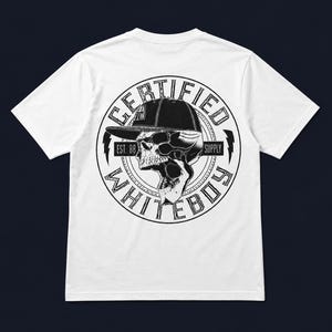 May include: White t-shirt featuring a black and white graphic. The graphic is a skull wearing a baseball cap, surrounded by a circular design with the words "CERTIFIED" and "WHITEBOY". The text "EST. 88" and "SUPPLY" are also included.