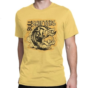 May include: Yellow t-shirt with a graphic design featuring a stylized monster with a tire for a mouth and the words "BULL SHIFTERS" in black. The design is on a yellow background.
