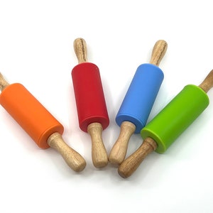 May include: Four colorful rolling pins with wooden handles and silicone rolling surfaces. The rolling pins are orange, red, blue, and green. The handles have text printed on them. These are kitchen tools for baking.