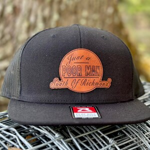 May include: Black and brown trucker hat with a brown leather patch that says "Just a Poor Man South of Richmond".