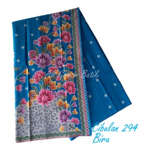 Puede incluir: Una tela batik azul con un patrón floral y un borde de espirales blancas y negras. La tela está doblada por la mitad y el texto "Cibulan 294 Biru" es visible en la esquina inferior derecha.