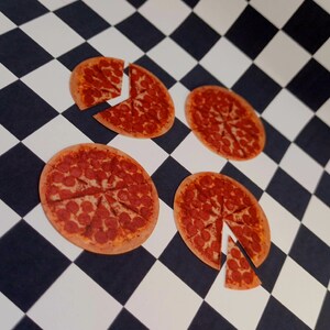 May include: Four mini pepperoni pizzas on a black and white checkered surface. Each pizza is cut into slices and has a red and brown crust.