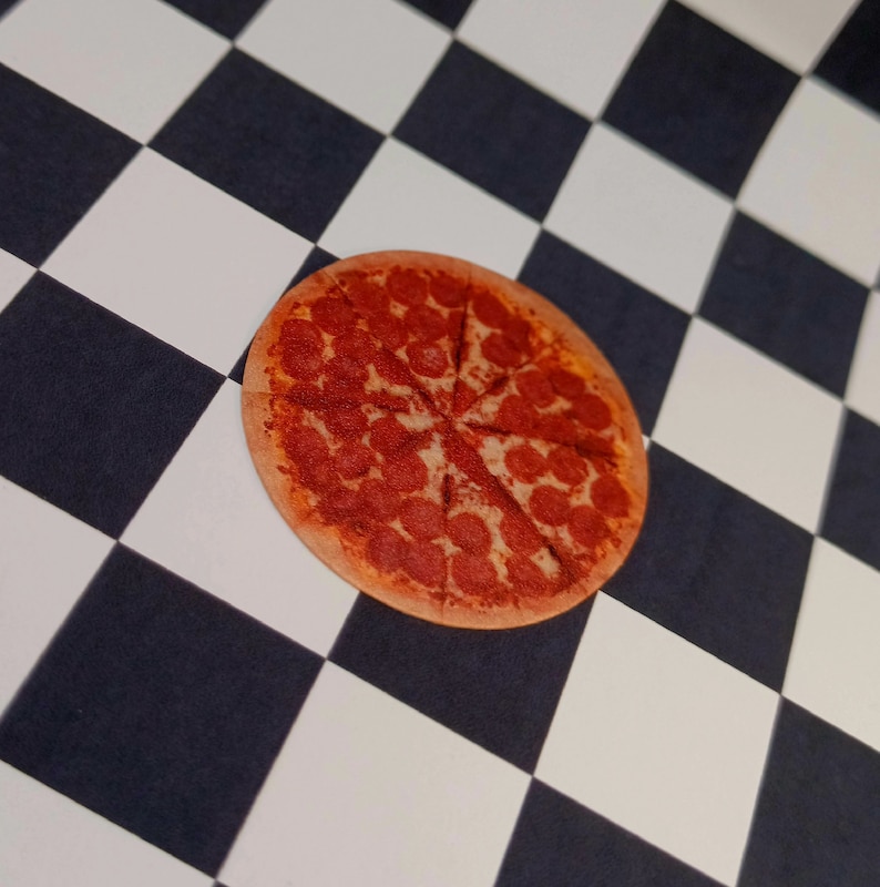 May include: A pepperoni pizza with a brown crust and red pepperoni slices on a black and white checkered background.