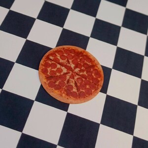 May include: A pepperoni pizza with a red sauce base and a golden brown crust. The pizza is sliced into eight pieces and is sitting on a black and white checkered surface.
