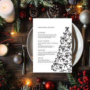 May include: A festive Christmas dinner menu on a white plate, featuring a black and white Christmas tree illustration. The menu lists Roasted Butternut Squash Soup, Herb-Roasted Turkey, and a Classic Yule Log. The table is decorated with festive ornaments.