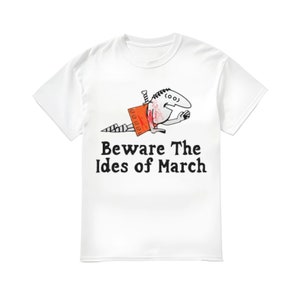 May include: White t-shirt with a black and white cartoon illustration of a person being stabbed with a knife. The text "Beware The Ides of March" is printed below the illustration.