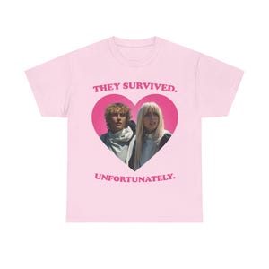 Peut inclure: Un t-shirt rose clair avec un motif central en forme de cœur contenant une photographie de deux personnes. Au-dessus du cœur se trouve le texte "THEY SURVIVED." et en dessous le texte "UNFORTUNATELY." en lettres capitales rose foncé.
