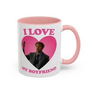 May include: White ceramic mug with a pink interior and handle. The mug features the text "I LOVE MY BOYFRIEND" in pink, with a pink heart shape containing an image of a man. A fun and romantic gift idea.
