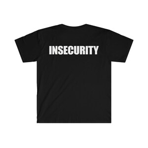 以下が含まれることがあります： 胸元上部に太字の白い大文字で「INSECURITY」という単語がプリントされた黒い半袖Tシャツ。この衣類はクルーネックで標準的なフィット感があり、無地の黒い背景にコントラストの強いテキストが配置されています。