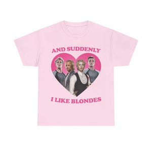 Könnte beinhalten: Ein hellrosa T-Shirt mit kurzen Ärmeln und einem großen dunkelrosa Herz-Aufdruck auf der Brust. Im Herz sind vier blonde Männer aus Hunger Games abgebildet. Der Text "AND SUDDENLY" steht darüber und "I LIKE BLONDES" darunter.