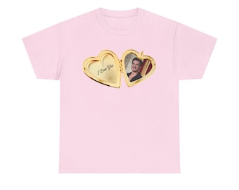 May include: A pale pink t-shirt with a gold heart-shaped locket design. The locket is open, displaying a photograph of a person. The locket has the words "I Love You" inscribed on it.