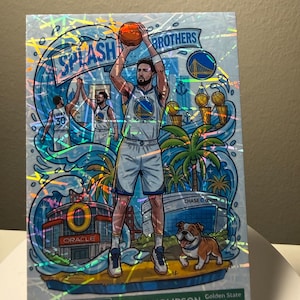 May include: A holographic trading card featuring Klay Thompson of the Golden State Warriors. The card has a colourful illustration of Thompson shooting a basketball, with the words "Splash Brothers" and "Downtown" visible.