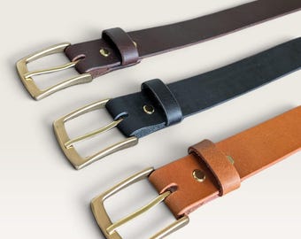 Peut inclure: Trois ceintures en cuir disposées en diagonale, comprenant une ceinture marron foncé, une noire et une beige. Chaque ceinture est dotée d'une boucle rectangulaire en métal doré, d'un passant assorti et d'un rivet métallique de fixation.