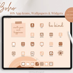 Op de afbeelding: Het scherm van een digitale tablet toont een set bruine en beige app-pictogrammen voor een iOS-apparaat. De pictogrammen zijn gerangschikt in een rasterpatroon en omvatten apps zoals Amazon, Muziek, Agenda, Camera, Foto's, Mail, Contacten, Herinneringen, Klok, Pinterest, FaceTime, TikTok, Facebook en meer. Het scherm heeft ook een beige achtergrond met een cirkelvormig patroon en de tekst "create your own happiness" en "be kind".
