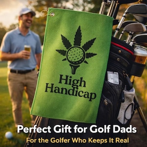 Può includere: Un asciugamano da golf verde con la scritta "High Handicap" e un disegno di una pallina da golf all'interno di una foglia di cannabis. L'asciugamano è appeso a una sacca da golf con mazze. Un uomo è visibile sullo sfondo.