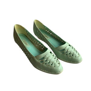 May include: A pair of light green woven leather flats with the brand name "Calico" printed on the insole.