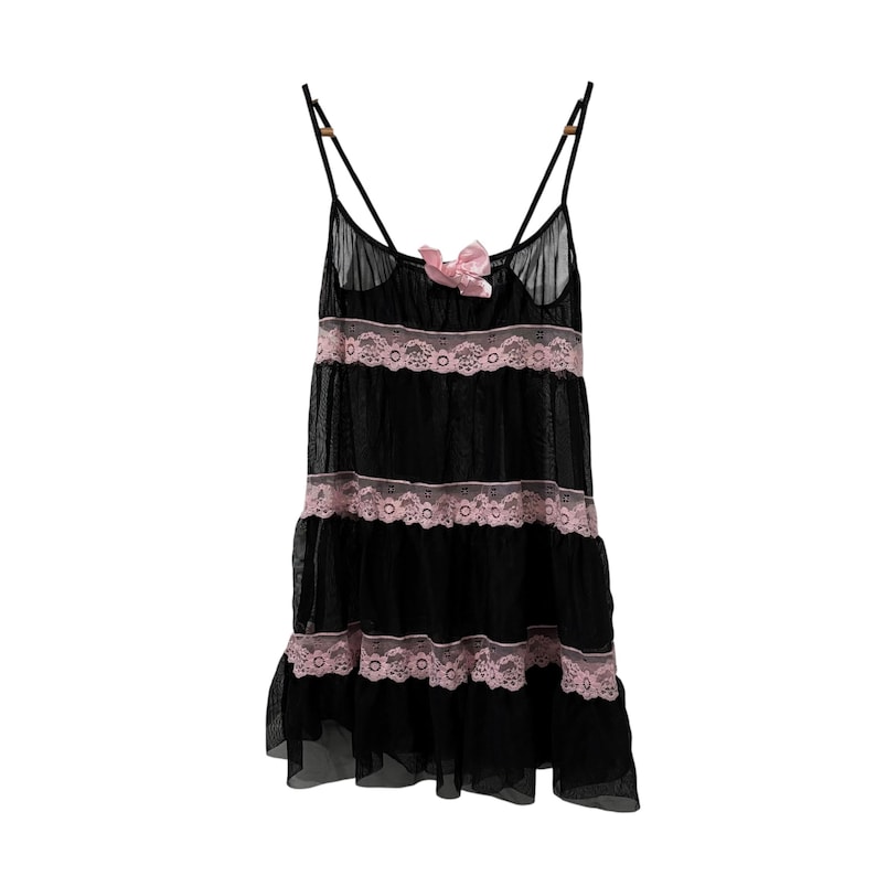 May include: Black babydoll lingerie with pink lace trim and a matching bow. The sheer fabric is layered with three tiers of pink lace. The straps are thin and adjustable.