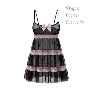 May include: Black babydoll lingerie with a sheer overlay and pink lace trim. The lingerie features a pink bow at the bust and spaghetti straps. The skirt has multiple tiers with lace detailing, creating a layered effect.
