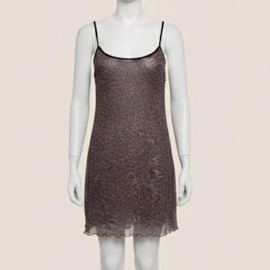 May include: A sleeveless mini dress featuring a dark brown and black leopard print pattern. The garment has thin black spaghetti straps, a scoop neckline, and a lettuce-edge hemline. The fabric appears semi-sheer with a fitted silhouette.