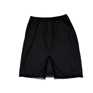 May include: Black slip skirt with a slit in the front. The skirt has a simple design with a lace trim at the bottom. The fabric appears to be a lightweight material.