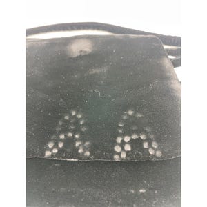 May include: A black velvet bag with a flap closure. The bag has a strap and a pattern of white dots on the front. The velvet material appears to be slightly worn.