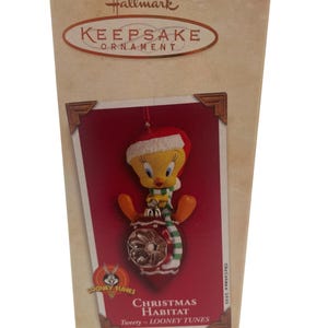 Könnte beinhalten: Ein Hallmark Keepsake Weihnachtsschmuck mit Tweety Bird von Looney Tunes. Der Schmuck befindet sich in einer Box mit dem Text "Christmas Habitat" und "Christmas 2003". Die Box ist beige mit roten und goldenen Akzenten.