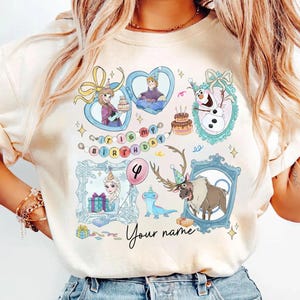 Könnte beinhalten: Hellbeige T-Shirt mit farbenfrohen Illustrationen von Figuren aus einem beliebten Zeichentrickfilm. Das Design umfasst gerahmte Porträts, Geburtstagskuchen und den Text "It's my birthday" und "Your name".