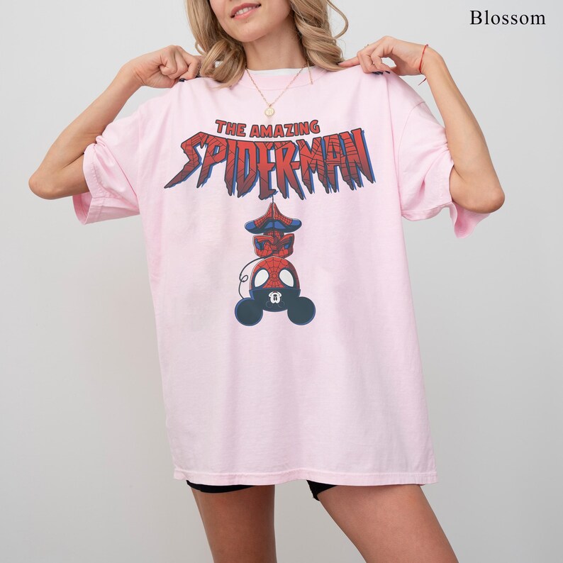 Pu&ograve; includere: T-shirt rosa chiaro con la scritta "THE AMAZING SPIDERMAN" in rosso e blu. Sotto, un'illustrazione di Spider-Man. La maglietta &egrave; di taglio ampio.