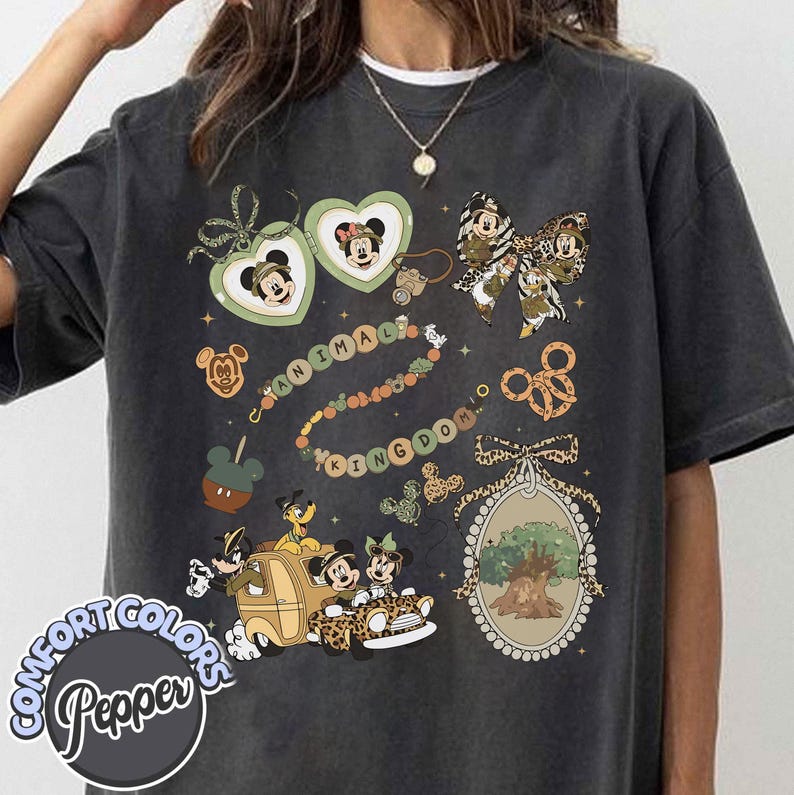 May include: Dark gray t-shirt with a colorful graphic design featuring Mickey and Minnie Mouse, along with the text "ANIMAL KINGDOM." The design includes heart-shaped lockets, a bow, and a car with animal print.