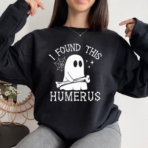 May include: Black sweatshirt with a white graphic of a ghost holding a bone with the text "I found this humerus".