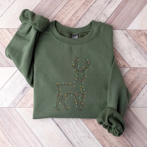 May include: A green sweatshirt with an embroidered design of a reindeer with Christmas lights.