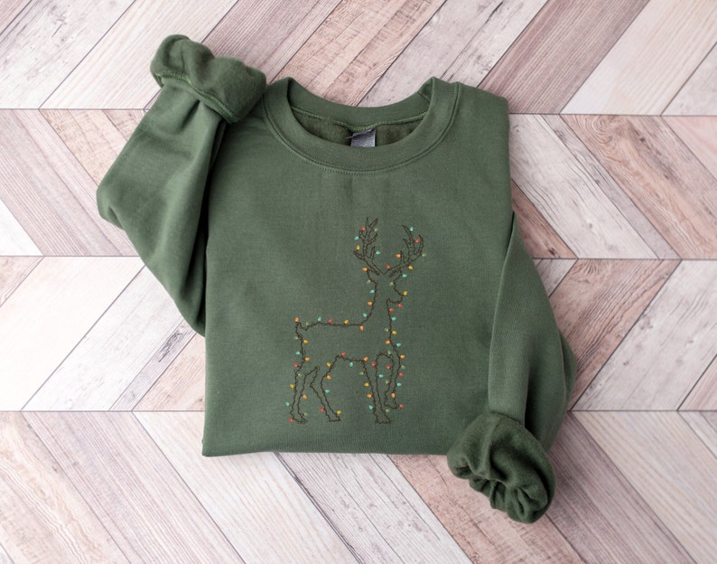 May include: A green sweatshirt with an embroidered design of a reindeer with Christmas lights.