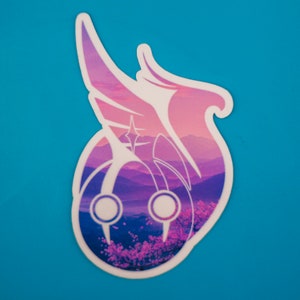 May include: A white sticker with a pink and purple mountain landscape design. The design features a stylized wing with a star in the center. The sticker is perfect for adding a touch of nature to your laptop, water bottle, or other belongings.