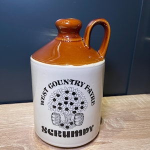 May include: A brown ceramic jug with a white design. The design features a tree with apples and the text "West Country Fav'rite Scrumpy".