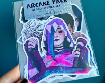 May include: A set of glossy stickers featuring characters from the animated series Arcane. The stickers are in a clear plastic bag and feature a variety of characters, including a woman with purple hair and a pink and blue outfit, a man with brown hair, and a woman with blue hair. The stickers are all in a cartoon style and are perfect for adding a touch of Arcane to your laptop, water bottle, or other belongings.