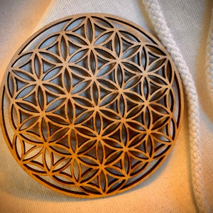 May include: A wooden wall hanging with a geometric design, known as the Flower of Life, in a light brown color.