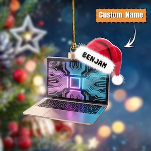 May include: A laptop Christmas ornament with a circuit board design on the screen. The ornament has a Santa hat with the name "BENJAM" and the text "Custom Name". The laptop is silver and has a gold string for hanging.