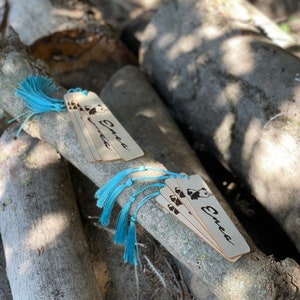 May include: A set of five wooden bookmarks featuring a panda bear design and the name "Enea" inscribed on them. Each bookmark has a blue tassel attached.