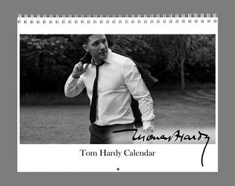 Könnte beinhalten: Ein spiralgebundener Wandkalender mit einem Schwarz-Weiß-Foto von Tom Hardy, der ein weißes Hemd und eine dunkle Krawatte trägt, mit einer Jacke über der Schulter. Der Text Tom Hardy Calendar und eine Unterschrift sind aufgedruckt.
