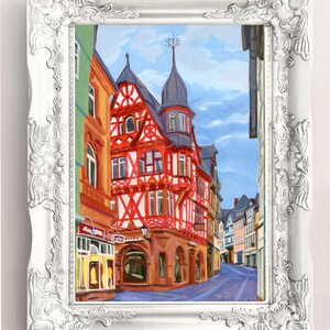 Pu&ograve; includere: Dipinto incorniciato di una scena di strada europea. L'opera raffigura edifici colorati con struttura in legno rossa e bianca, un cielo blu e una strada acciottolata. La cornice &egrave; bianca con dettagli ornati.