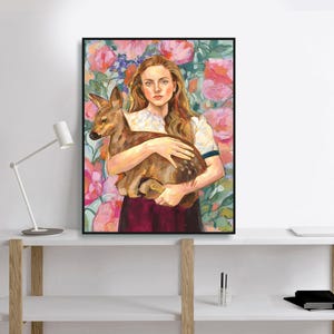 May include: A framed art print featuring a woman holding a fawn. The woman has long auburn hair and is wearing a white shirt with a dark red skirt. The background is a floral pattern with pink and green hues.