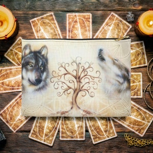 May include: A beige canvas zippered pouch with a design of two wolves on either side of a stylized tree. The wolves are facing opposite directions, one howling at the moon. The tree has a brown trunk and swirling branches.