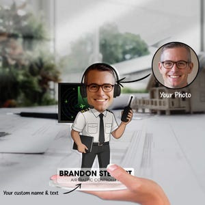 May include: A personalized acrylic figurine of an air traffic controller, featuring a cartoon likeness with a headset and radio. The figurine includes the text "BRANDON STEWART AIR TRAFFIC CONTROLLER" and a space for a custom photo.